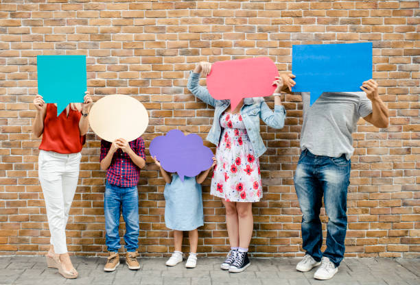 istock Family holding blank colorful speech bubbles by a brick wall 1072323300