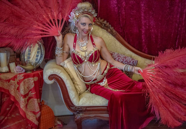 istock Belly dancer rests with red fans on Chaise Lounge. 1072346962