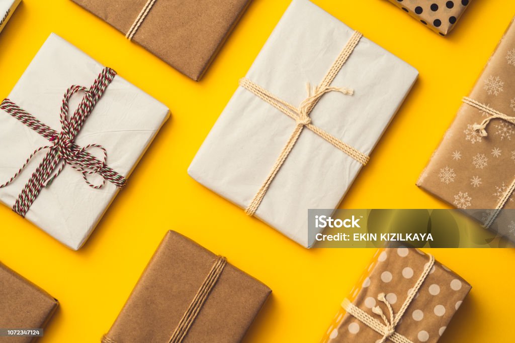 Gift box flat lay on yellow background Gift boxes packaged with wrapping papers on yellow background. Directly above table top shot. Flat lay presents. Gift Stock Photo