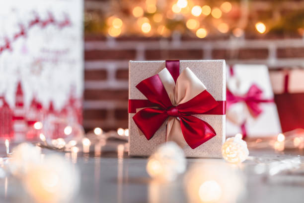 istock Wrapped gift with red ribbon on fireplace background 1072348644