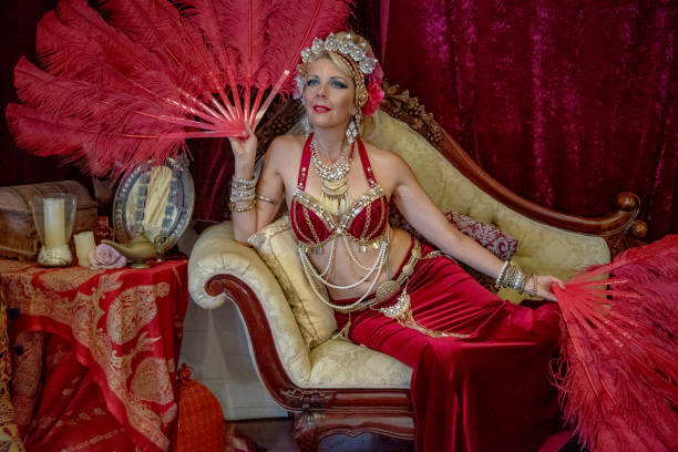istock Belly dancer rests with red fans on Chaise Lounge. 1072349424