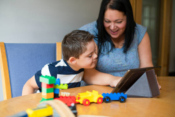 madre che insegna al figlio da una tavoletta - block togetherness happiness indoors foto e immagini stock