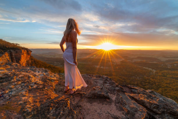 istock Girl standing on cliff ledge watching stunning sunset with views 1072349542