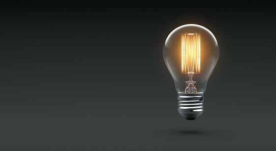 Glowing Edison light bulb on dark background - 3D Rendering