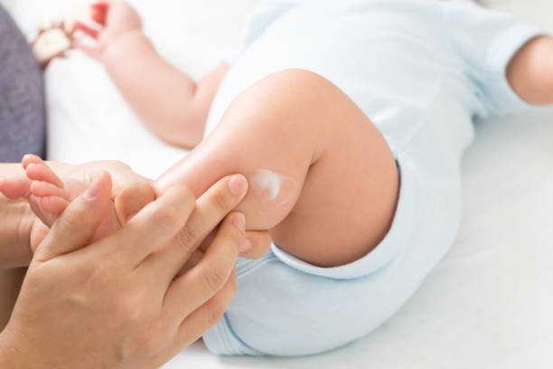 Mother is applying cream to the baby boy which helps to maintain skin leg hydration, Skincare and moisturizing cream concept Mother is applying cream to the baby boy which helps to maintain skin leg hydration, Skincare and moisturizing cream concept moisturizing cream stock pictures, royalty-free photos & images