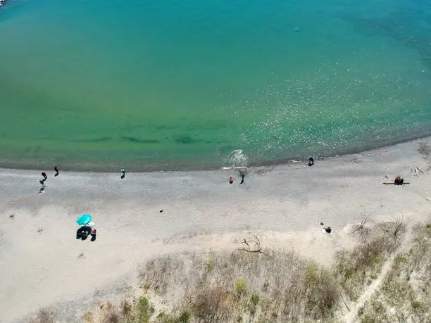 Photo of Aerial view of sandy beach with tourists swimming in beautiful clear lake water. Top view of people sunbathing lying down on the tropical beach summer travel holidays bird eye view.