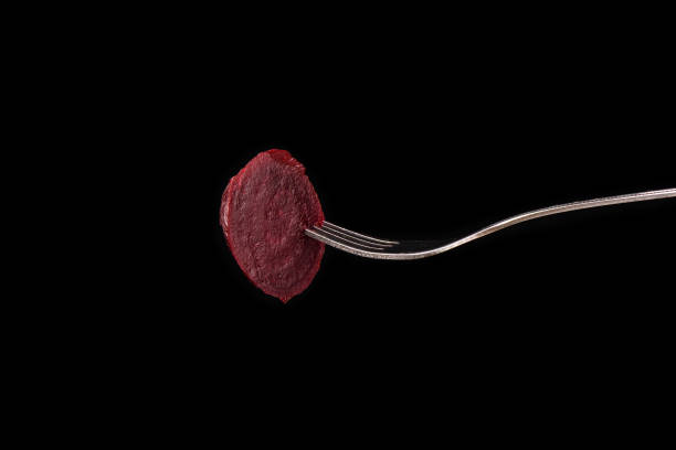 istock Slice of boiled beets on a fork isolated on a black background 1072356120