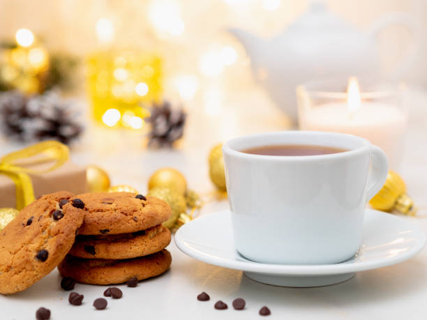 biscuits aux brisures de chocolat, tasse de thé sur fond clair de noël. agréable soirée, tasse de boisson, décorations de noël, bougies et guirlandes de lumières - russian culture scarf textile shawl photos et images de collection