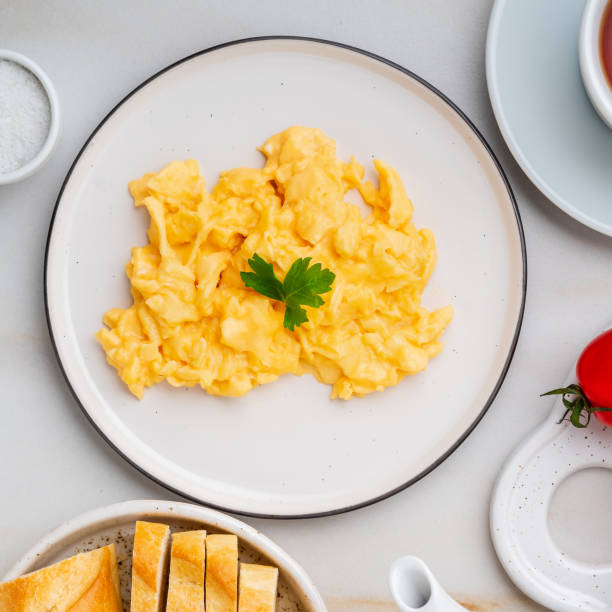 istock Scrambled eggs, Omelette. Breakfast with pan-fried eggs, cup of tea, tomatoes on white stone marble background. Top view 1072387342