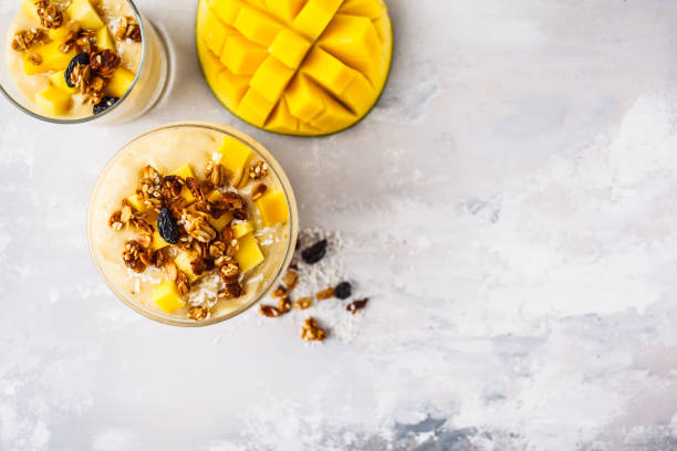istock Mango smoothie with granola and coconut in a jar, top view. 1072388408