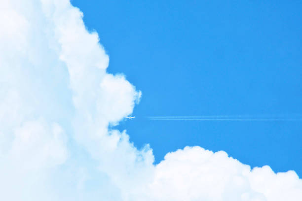 istock Airplane with white contrail flying into the big clouds with blue sky. Minimal background. 1072395946