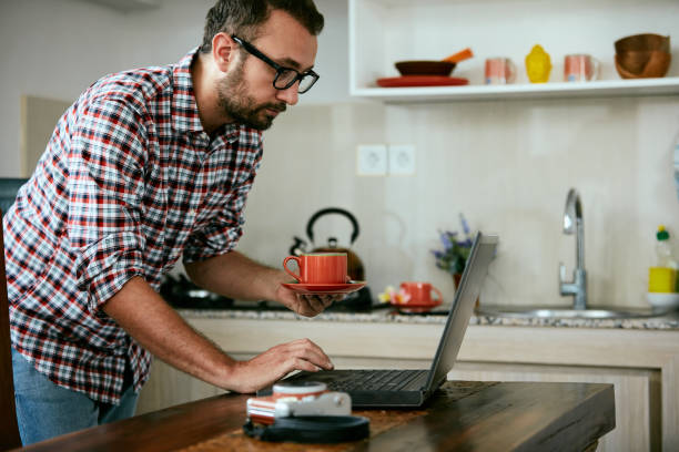 istock Modern bearded man using cellphone and drinking coffee with laptop. 1072402092