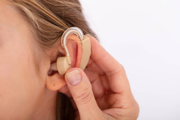Close-up Of A Doctor Hand Inserting Hearing Aid In Girl's Ear