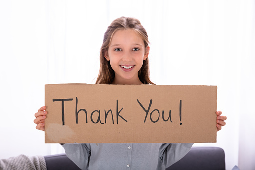 Portrait Of A Happy Girl Holding Thank You Placard