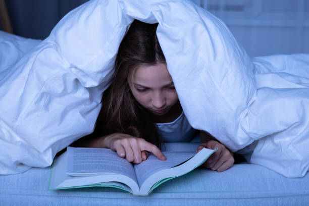 istock Girl Reading Book At Night 1072407258