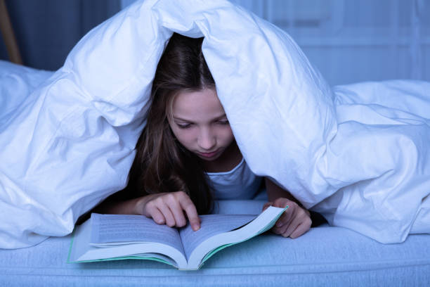 istock Girl Reading Book At Night 1072407262