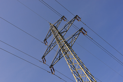 Electricity pylon with high voltage power line in front of blue sky