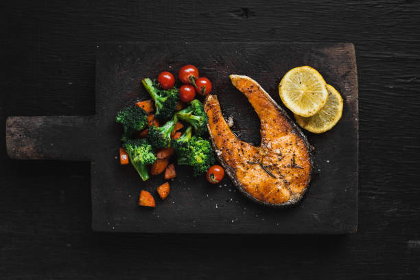 istock Salmon steak And vegetables on Black chopping Wood 1072420854