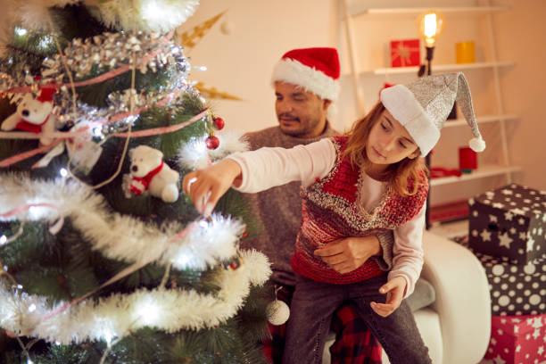 istock Father and daughter decorating cristmas tree together at home. 1072427634