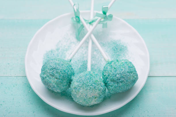 istock three turquoise cake pop in sugar on a white plate, on turquoise boards 1072433138