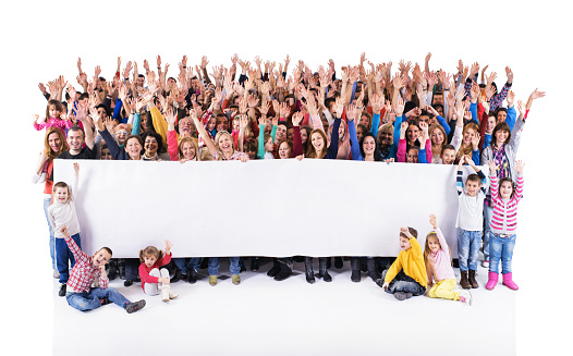 Crowd of happy people with raised arms holding big white banner for commercials and looking at camera.  Isolated on white. Copy space.
