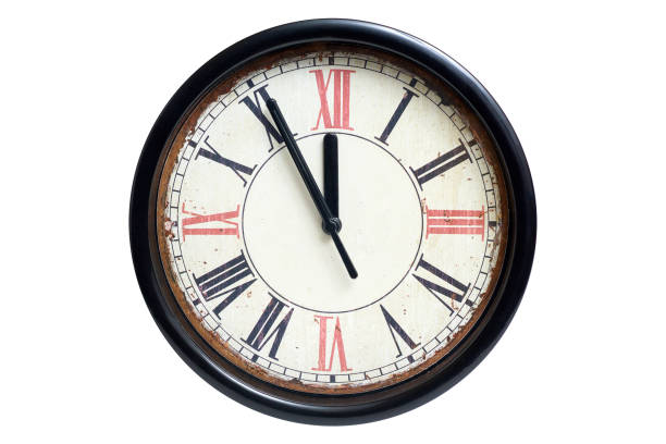 istock Old style classic clock with roman numbers showing almost twelve o' clock isolated on white background, front view 1072438676