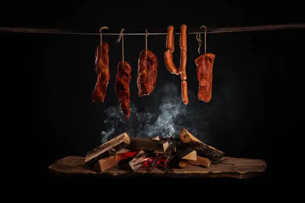 Smoked ham, bacon, pork neck and sausages in a smokehouse.