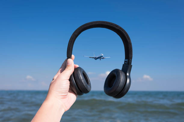 Female hands with headphones on the sea wave and landing plane background. Female hands with headphones on the sea wave and landing plane background. Concept backside for a girl on the beach stock pictures, royalty-free photos & images