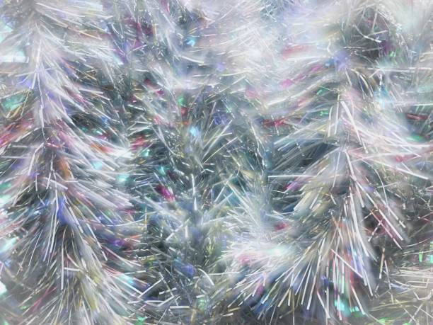 Holiday background of shiny silver tinsel with little spots of glowing color in a full frame close-up