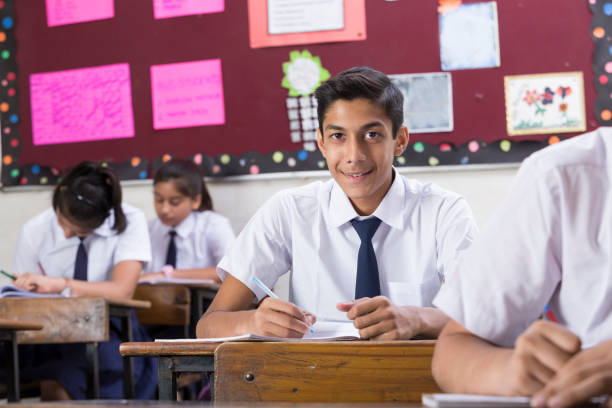 istock Male student in classroom writing in notebook - Stock image 1072469968