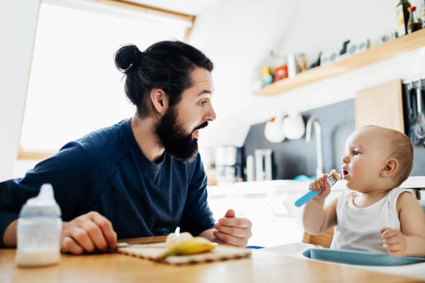 istock Single Father Helping Baby Eat Lunch 1072470588