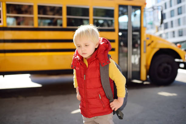 istock Pupil with schoolbag with yellow school bus on background 1072472412