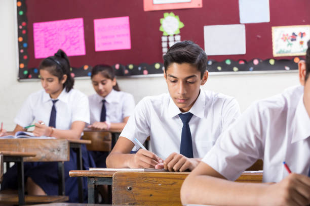 Male student in classroom writing in notebook - Stock image Classroom, School Building, Writing, Working, India, school test results stock pictures, royalty-free photos & images