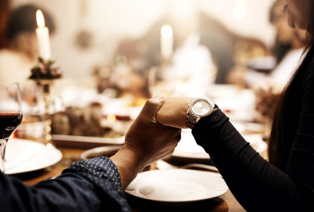 Cropped shot of unrecognizable people holding hands in prayer before having a Christmas lunch together