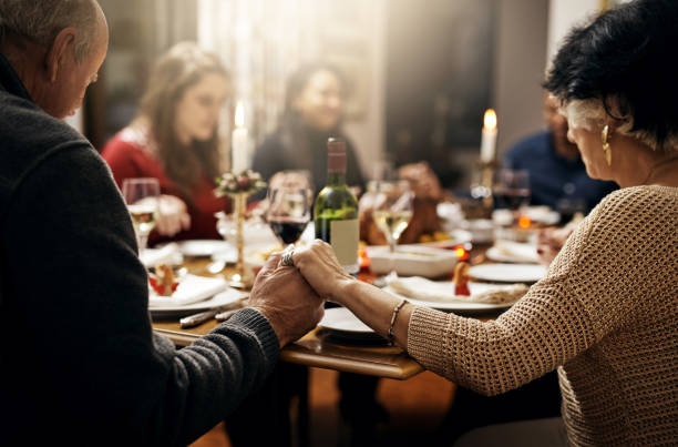 We thank you for your blessings Shot of family holding hands in prayer before having a Christmas lunch together saying grace stock pictures, royalty-free photos & images