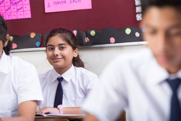 istock Female student in classroom writing in notebook - Stock image 1072473384