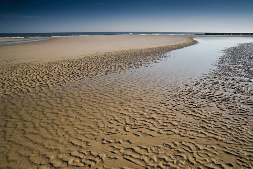 Sandbar, tidal pool and rippled sand during low tide in wadden sea under deep blue sky. Wangerooge Island, Friesland - district, Lower Saxony, Germany, Europe.
