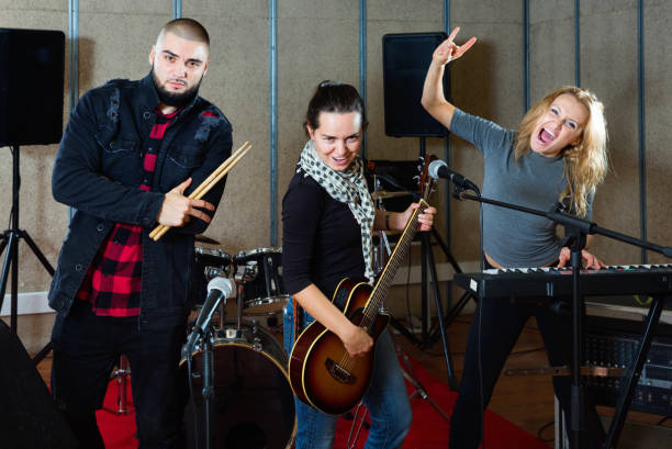 istock Three bandmates posing together with musical instruments in rehearsal room 1072487484