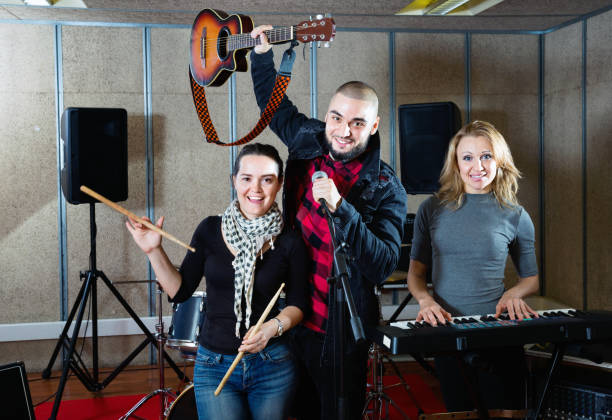 istock Three bandmates posing together with musical instruments in rehearsal room 1072487486