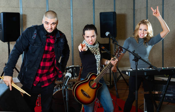 istock Three bandmates posing together with musical instruments in rehearsal room 1072487488