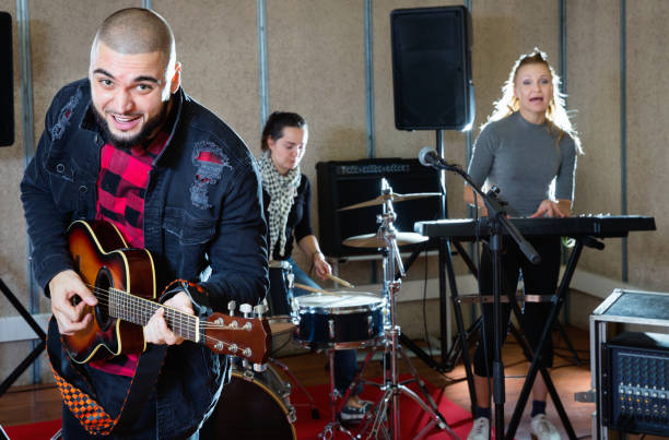 istock Guy guitar player and singer practicing with band members in recording studio 1072487502