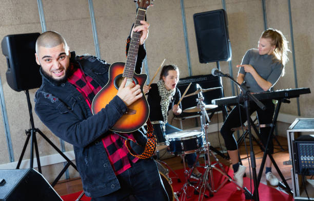 istock Guy guitar player and singer practicing with band members in recording studio 1072487538