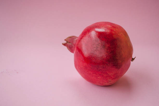 istock Ripe pomegranate fruit on a pastel colored pink background. 1072487934