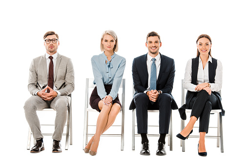 professional businesspeople sitting on chairs and looking at camera isolated on white