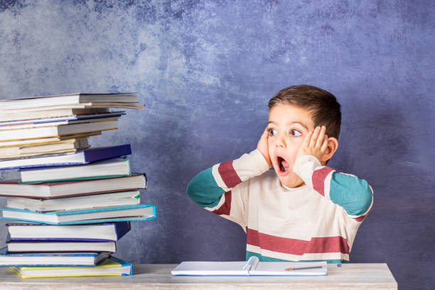 istock Little kid stressed doing homework with a stack of books 1072503750