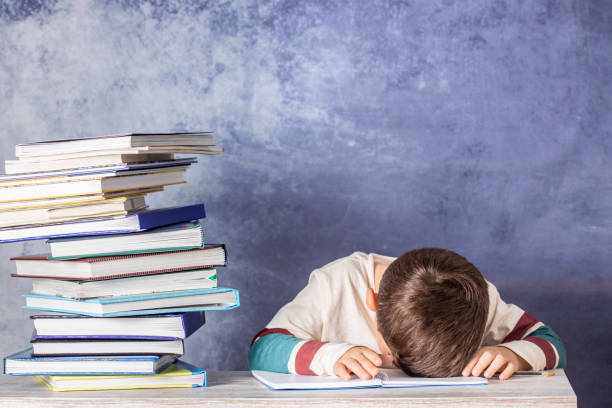 istock Little kid stressed doing homework with a stack of books 1072503764