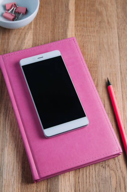 istock Pink notebooks and smartphone on the table 1072505676