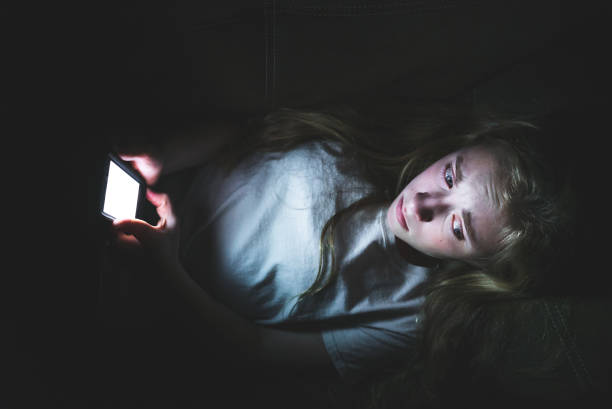 istock Depressed girl on her smartphone while lying down in the dark. 1072510962