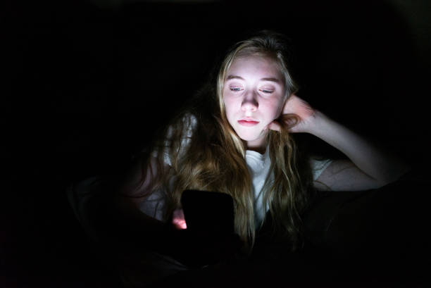 istock Depressed girl on her smartphone while lying down in the dark. 1072512958