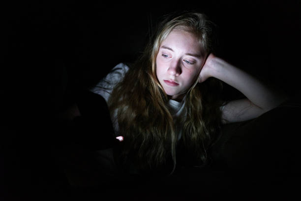 istock Depressed girl on her smartphone while lying down in the dark. 1072515164